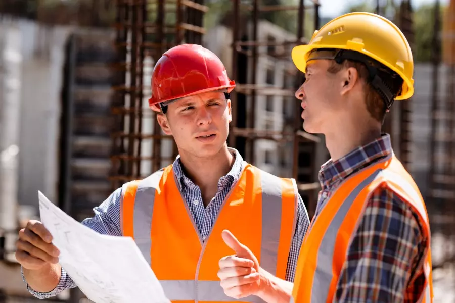Ingeniero civil y jefe de obra de construcción con planos en edificio